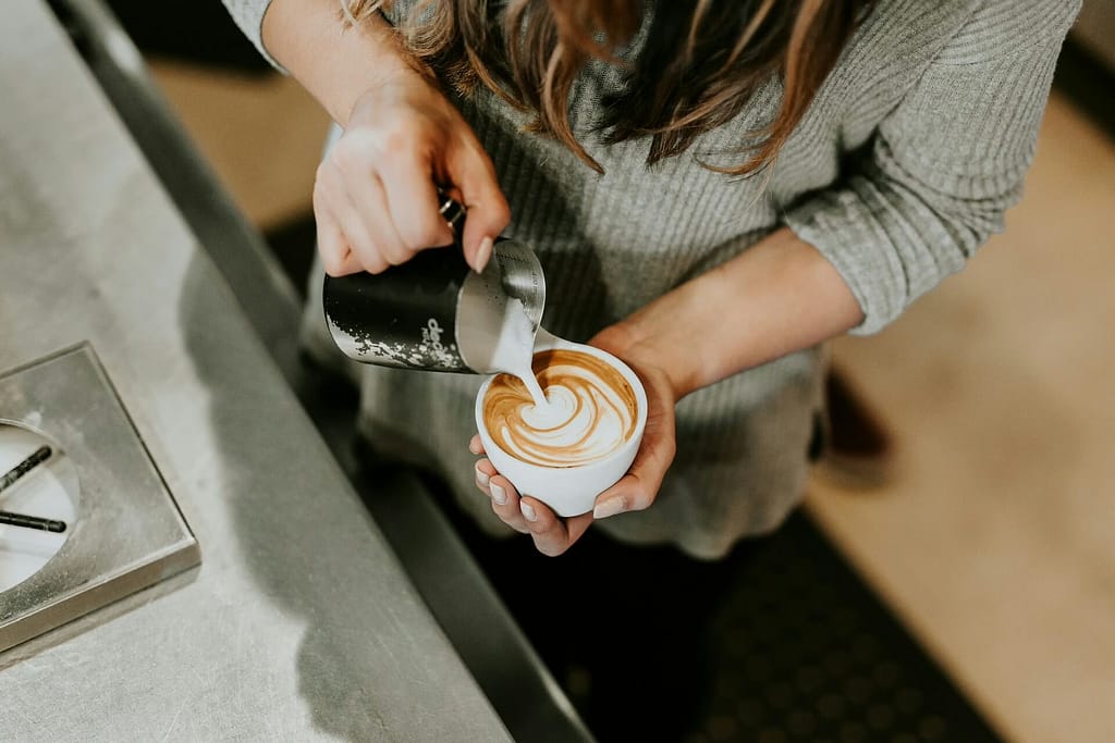 Barista pouring milk into coffee to create latte art