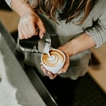 Barista pouring milk into coffee to create latte art