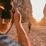 Traveler walking through a canyon at sunset while being photographed